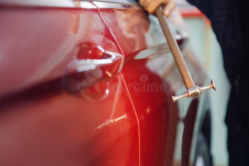 Master auto mechanic removal of dents defects without painting on car body on service station.