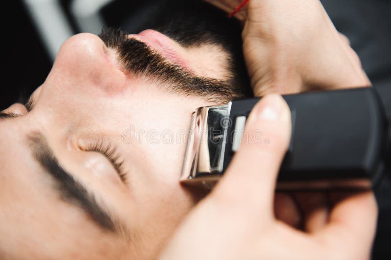 Master cuts hair and beard of men in the barbershop, hairdresser makes hairstyle for a young man. stock image Master cuts hair and beard of men in the barbershop, hairdresser makes hairstyle for a young man. stock image