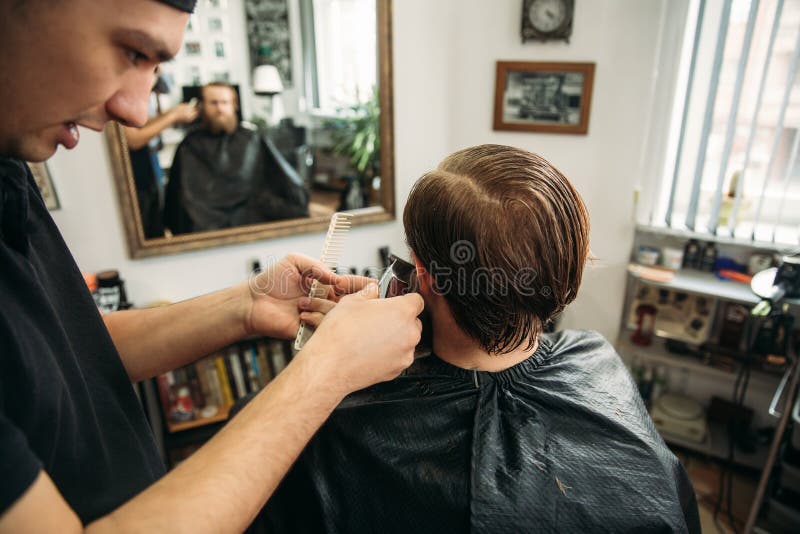 Master cuts hair and beard of men in the barbershop, hairdresser makes hairstyle for a young man stock images Master cuts hair and beard of men in the barbershop, hairdresser makes hairstyle for a young man stock images