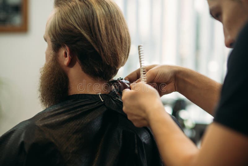 Master cuts hair and beard of men in the barbershop, hairdresser makes hairstyle for a young man royalty free stock images Master cuts hair and beard of men in the barbershop, hairdresser makes hairstyle for a young man royalty free stock images