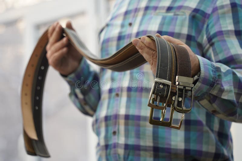 The Master Holds Handmade Leather Belts with Buckles in His Hands Stock