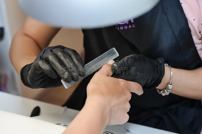 The master of manicure makes a nail polish, shapes the oval royalty free stock images The master of manicure makes a nail polish, shapes the oval royalty free stock images