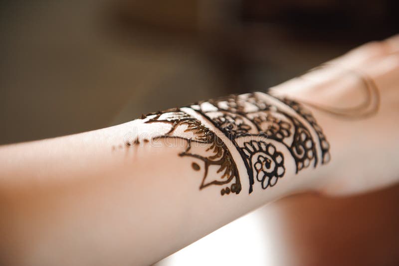 Master mehndi draws henna on a female hand.