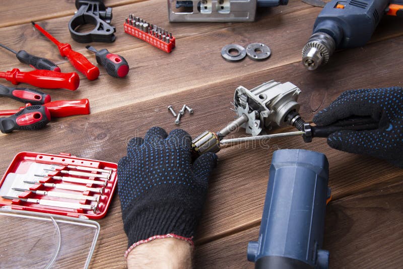 The master repairs a broken electrical device: drill, cutter on a wooden table. Electric Tool Repair Shop royalty free stock photos The master repairs a broken electrical device: drill, cutter on a wooden table. Electric Tool Repair Shop royalty free stock photos