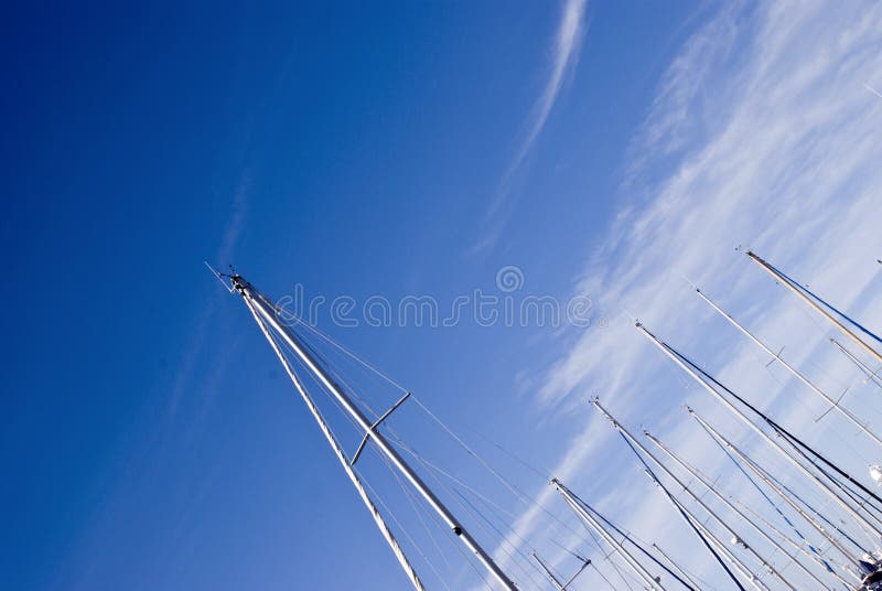 Masts against the cloudy blue sky background. Masts against the cloudy blue sky background