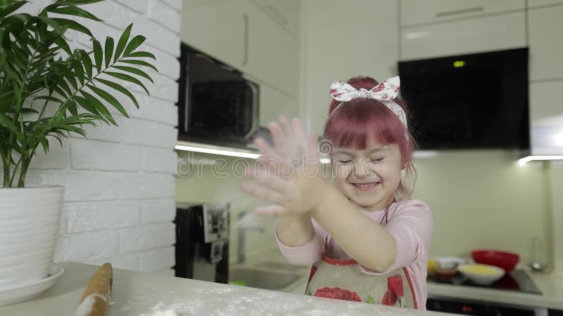 Mata pizza. Ett litet barn som leker med mjöl får sina händer smutsiga i köket