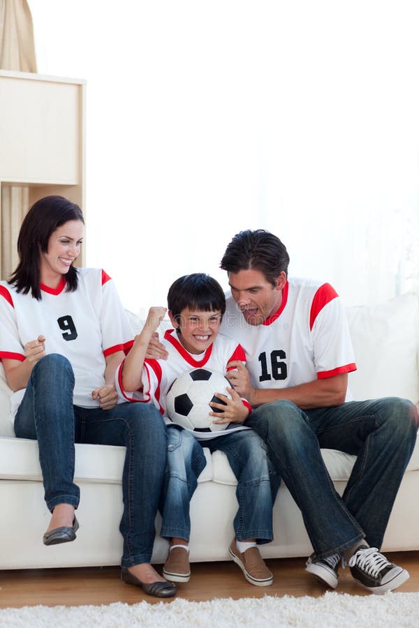 Match de football de observation de famille joyeuse sur le televisio image stock Match de football de observation de famille joyeuse sur le televisio image stock