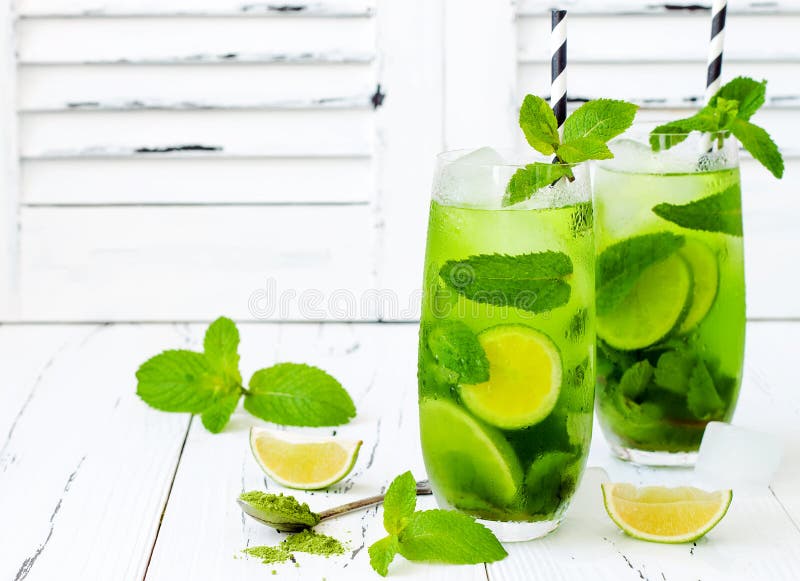 Matcha iced green tea with lime and fresh mint on white rustic background. Super food drink.