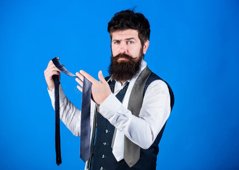 Matching with business suit. Brutal caucasian man choosing fashion accessories. Bearded fashion model with formal look. Hipster with long beard and moustache in classic fashion style. Man of fashion.