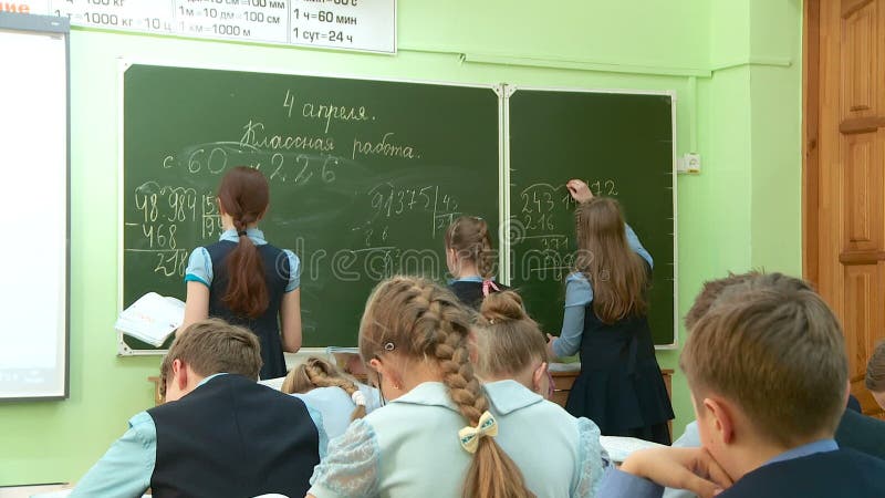 Matematikkurs på skolbarn att lösa problem på svart tavla och på deras skrivbord