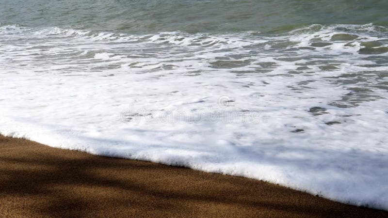 Material de archivo de vídeo en el que se ve la sombra de las olas que se lavan la arena en un día soleado almacen de video