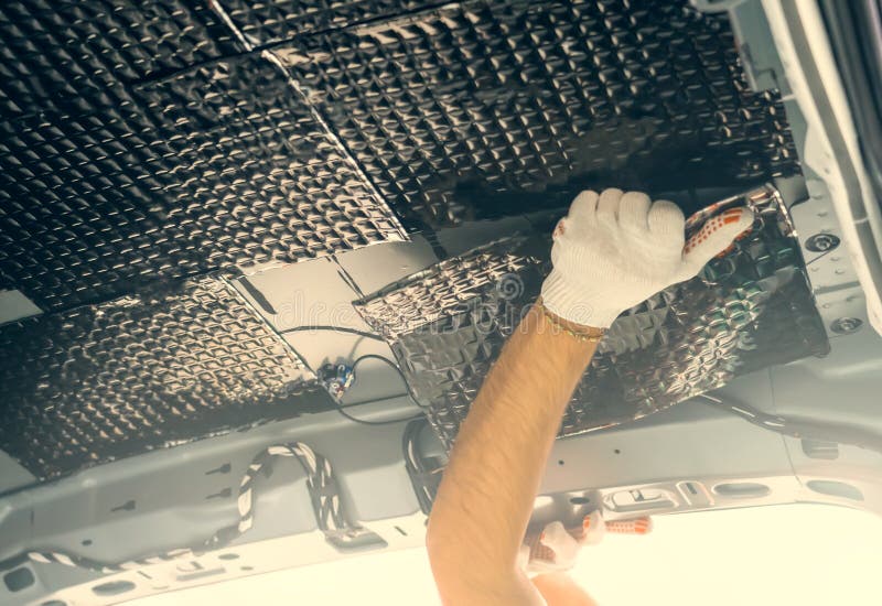 Las manos de los trabajadores pegan material de insonorización al interior  del techo del coche. Proceso de instalación del aislamiento acústico del  coche Fotografía de stock - Alamy