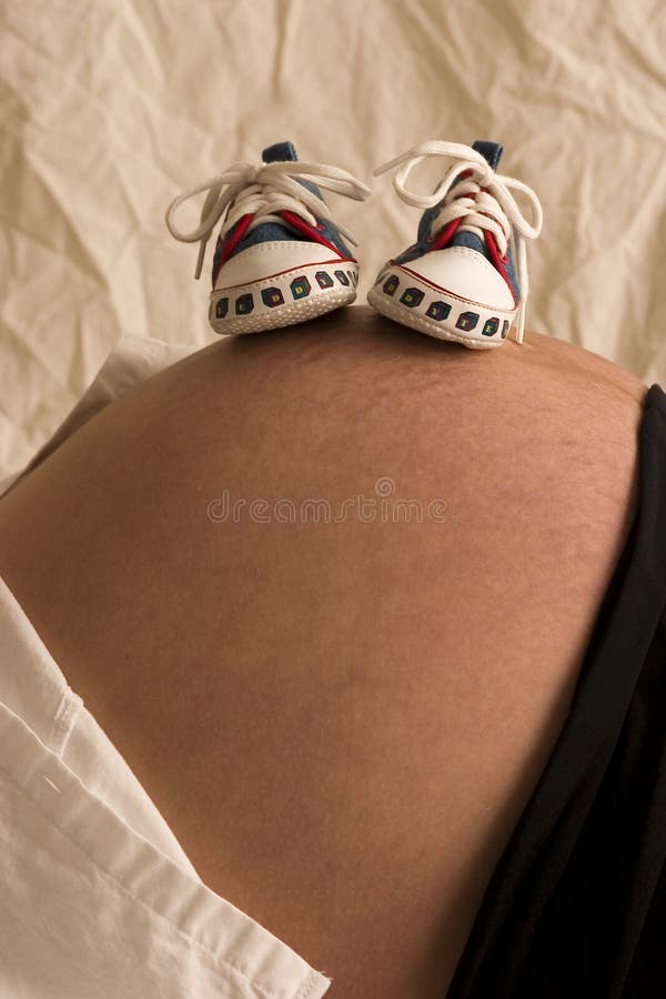 An expecting mom with baby shoes on her tummy. An expecting mom with baby shoes on her tummy