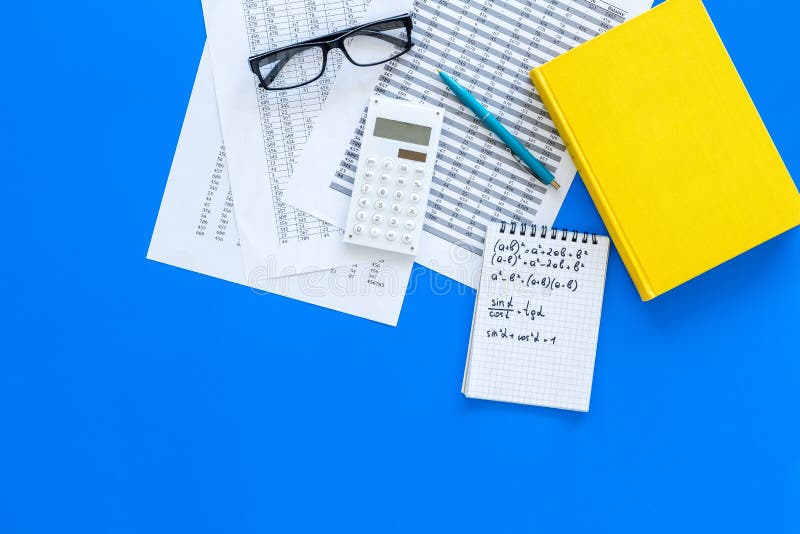 Math homework. Math textbook or tutorial near sheet with numbers, countes, calculator, notebook with formula on blue stock photo