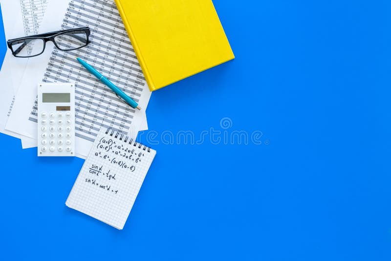 Math homework. Math textbook or tutorial near sheet with numbers, countes, calculator, notebook with formula on blue royalty free stock photo
