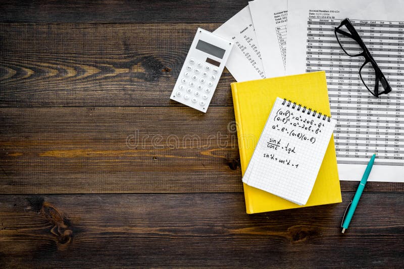 Math homework. Math textbook or tutorial near sheet with numbers, countes, calculator, notebook with formula on dark royalty free stock photography
