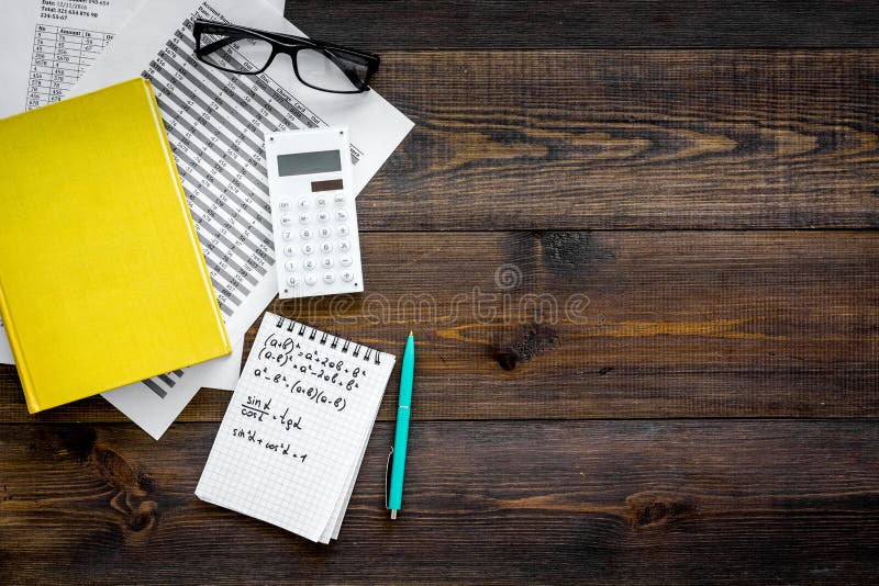 Math homework. Math textbook or tutorial near sheet with numbers, countes, calculator, notebook with formula on dark royalty free stock photography