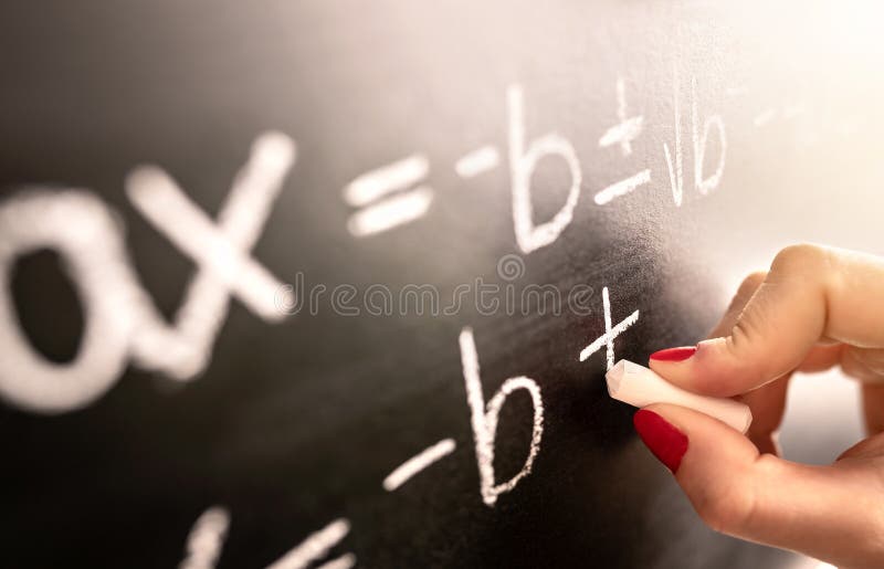 Math teacher writing function, equation or calculation on blackboard in school classroom. stock image