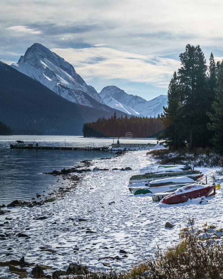 Matin froid avec la neige couvrant des canoës dans le lac de maligne, Alberta, Canada image stock Matin froid avec la neige couvrant des canoës dans le lac de maligne, Alberta, Canada image stock