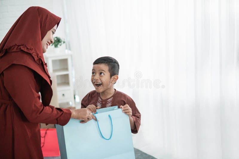 Asian mother give gifts to their son using paper bag when Eid Mubarak. Asian mother give gifts to their son using paper bag when Eid Mubarak