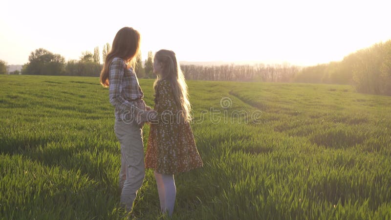 Matka i córka stoją na zielonym polu wieczorowym
