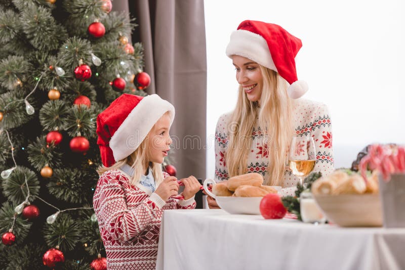 Matka i córka w swetrach i kapeluszach santa uśmiechają się i mówią zdjęcie stock