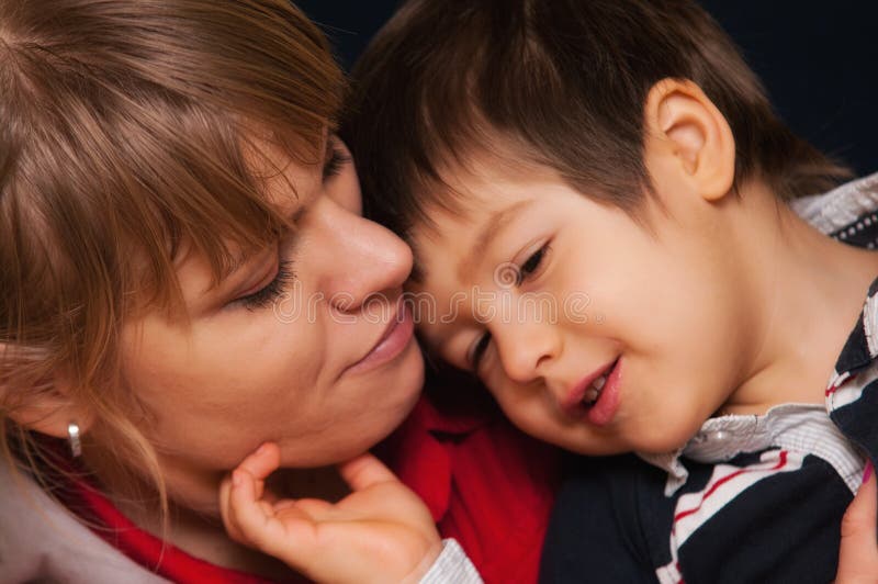 Portrait of pretty young mother with her face touching that of her son both looking happy and contented. Portrait of pretty young mother with her face touching that of her son both looking happy and contented.