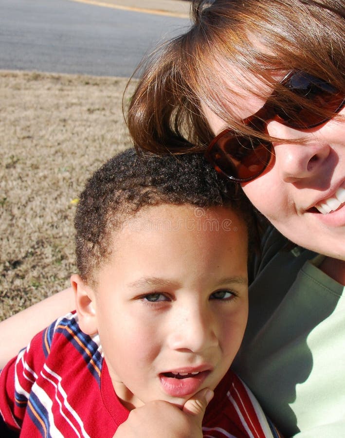 A mother and her adopted son sit outside together on a bright summer day. A mother and her adopted son sit outside together on a bright summer day