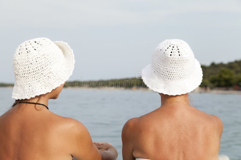 Matki i córki obsiadanie na dennym brzeg, pogodna plaża fotografia stock Matki i córki obsiadanie na dennym brzeg, pogodna plaża fotografia stock
