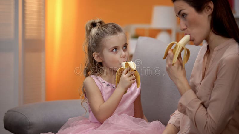 Matki i córki łasowania banany, zdrowy styl życia, organicznie odżywianie, dieta zdjęcie stock Matki i córki łasowania banany, zdrowy styl życia, organicznie odżywianie, dieta zdjęcie stock