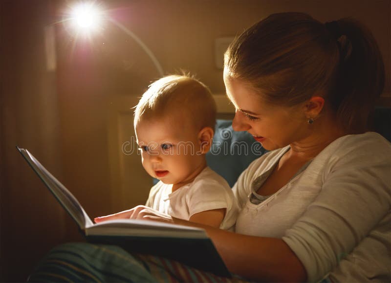 Mother and baby son reading a book in bed before going to sleep. Mother and baby son reading a book in bed before going to sleep