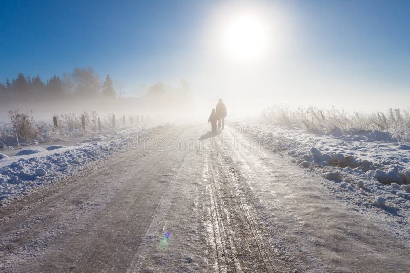 Mother and child on foggy snow road near farm and fence. Mother and child on foggy snow road near farm and fence