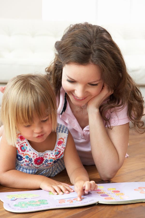 Matriz e filha que aprendem ler em casa imagens de stock Matriz e filha que aprendem ler em casa imagens de stock
