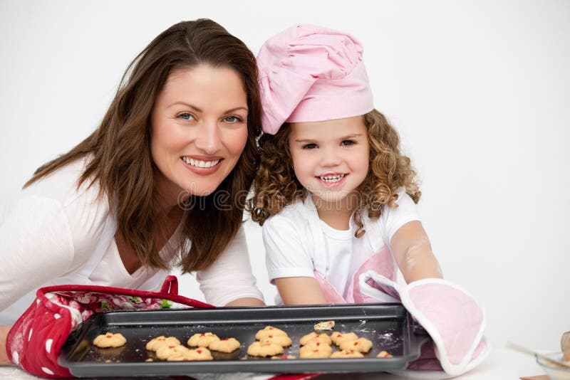 Lovely mother and daughter holding a plate with biscuits in the kitchen. Lovely mother and daughter holding a plate with biscuits in the kitchen