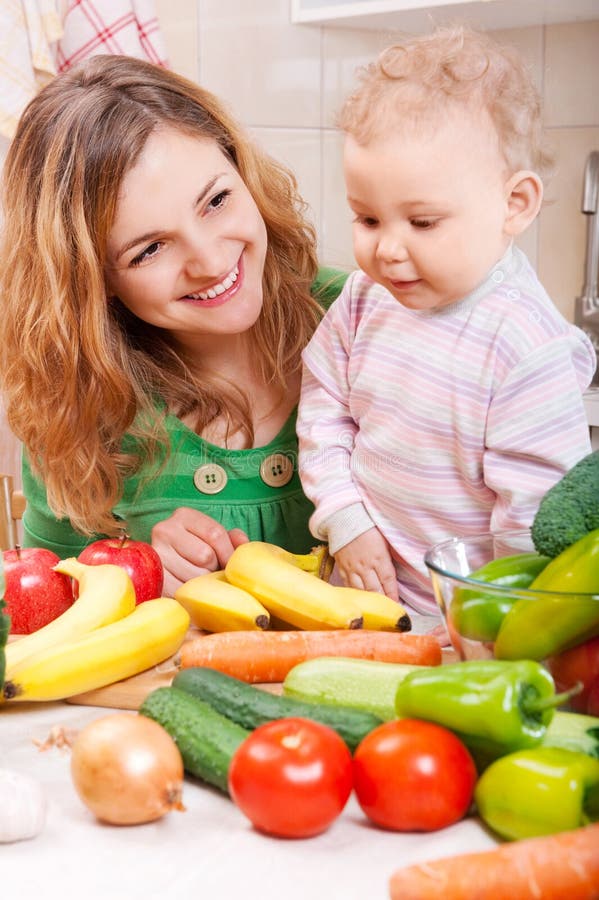 Mãe feliz com a filha a preparar legumes imagens de stock