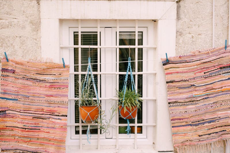 The Mats Patchwork are Dried Near a White Window with a Grille and Two
