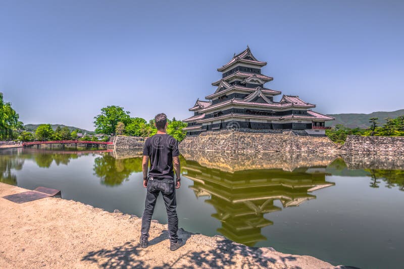 Matsumoto - 25 de maio de 2019: O castelo de Matsumoto e a ponte vermelha que o leva, Japão fotografia de stock Matsumoto - 25 de maio de 2019: O castelo de Matsumoto e a ponte vermelha que o leva, Japão fotografia de stock