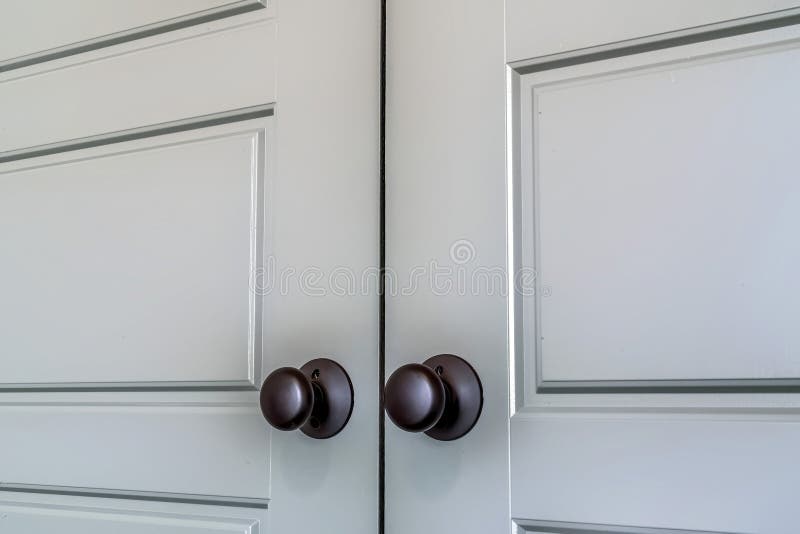 Matte Black Round Door Knobs of a Double Door with Paneling Inside a