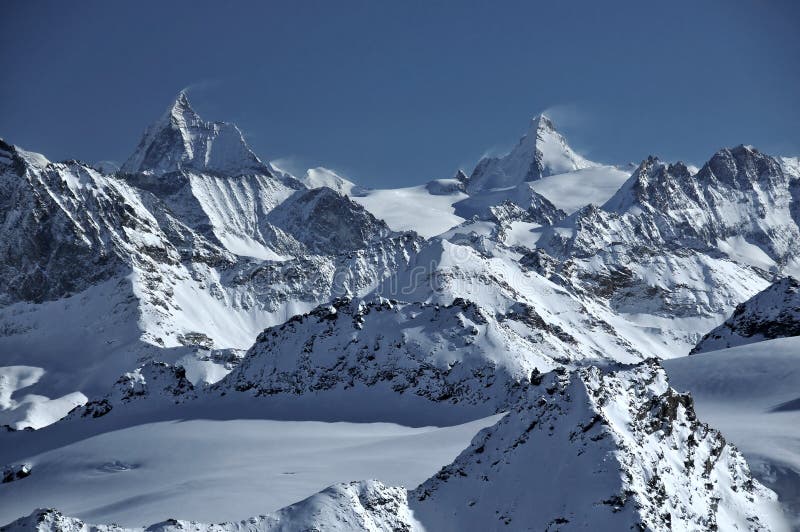 Matterhorn and Dent d'Herens. Two swiss giants with plumes of blown snow. The matterhorn and the Dent d'Herens. In the background Castor and Pollux. In the stock images Matterhorn and Dent d'Herens. Two swiss giants with plumes of blown snow. The matterhorn and the Dent d'Herens. In the background Castor and Pollux. In the stock images