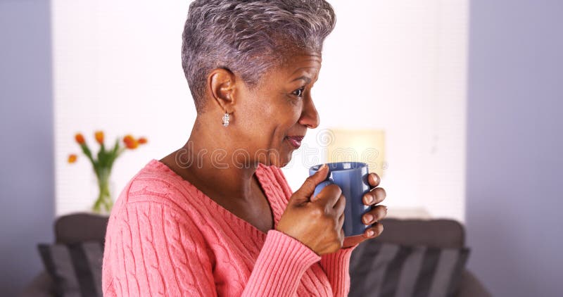 Mature African woman smiling with coffee mug imagen de archivo Mature African woman smiling with coffee mug imagen de archivo