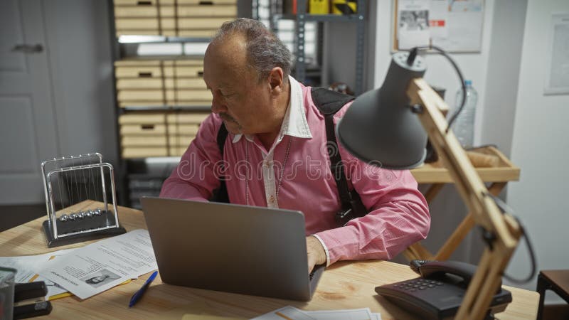 Mature bald man in a detective office analyzing evidence with laptop and paperwork. Detective paperwork stock images, royalty-free photos and pictures