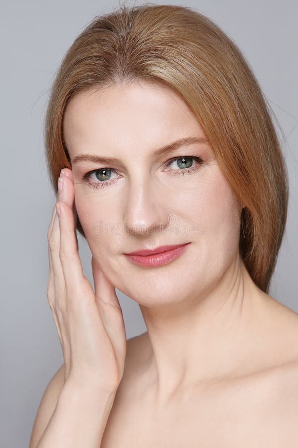 Portrait of attractive mature woman with clean skin touching her face. Portrait of attractive mature woman with clean skin touching her face