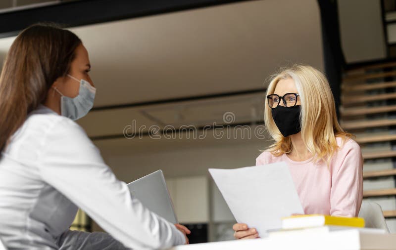 Mature female hr manager in a face mask reading cv royalty free stock photos
