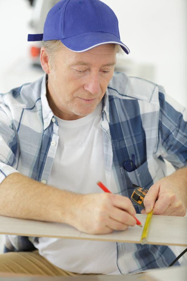 Mature Measuring Wooden Plank Using Tapeline Stock Photo