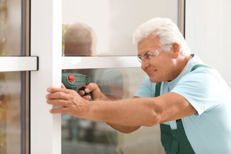 Mature construction worker repairing plastic window with electric screwdriver royalty free stock image Mature construction worker repairing plastic window with electric screwdriver royalty free stock image