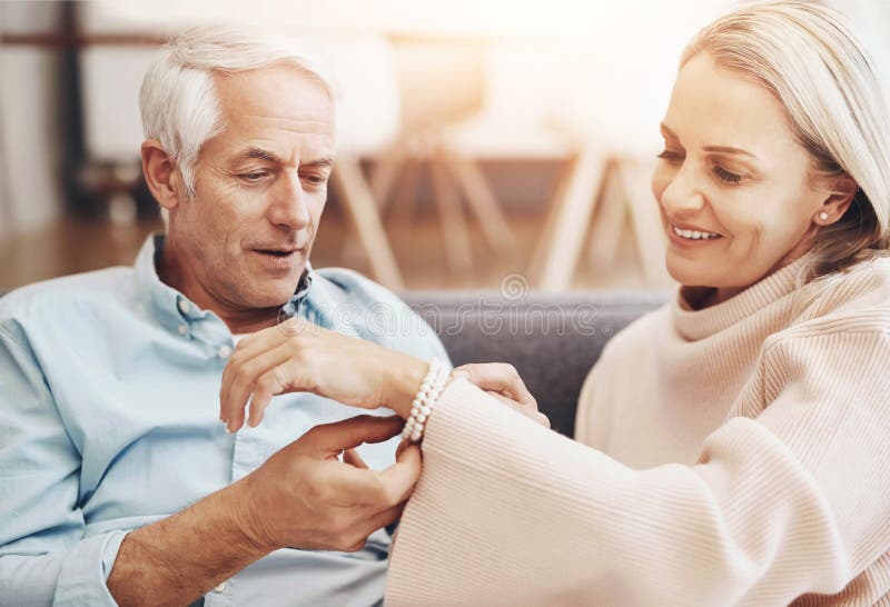 Mature couple, gift and home with jewelry for anniversary, love and romantic gesture in living room. Happy woman, sofa royalty free stock photos