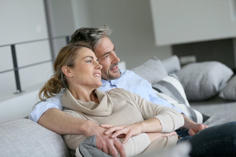 Mature couple sitting on couch embracing stock photography Mature couple sitting on couch embracing stock photography
