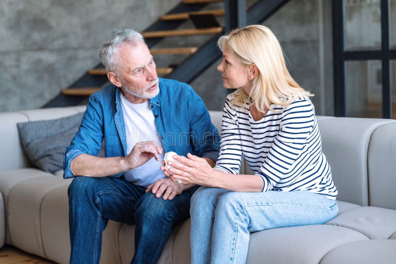 Cuplu matur care stă pe canapea și vorbește despre relații stock image