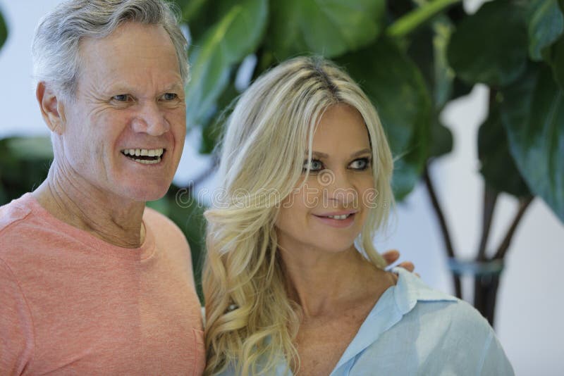 Image of a mature man and younger wife smiling off camera