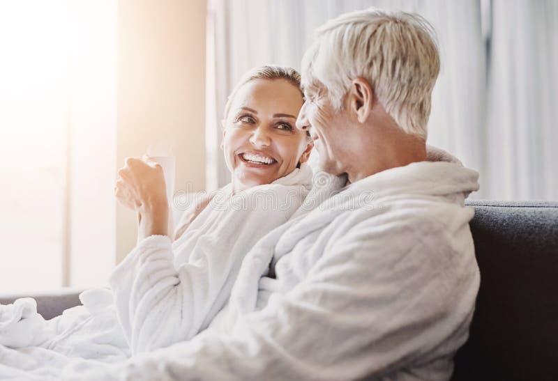 Mature couple, sofa and relax with coffee in gown or robe for luxury spa day together at resort. Senior man or woman royalty free stock photography